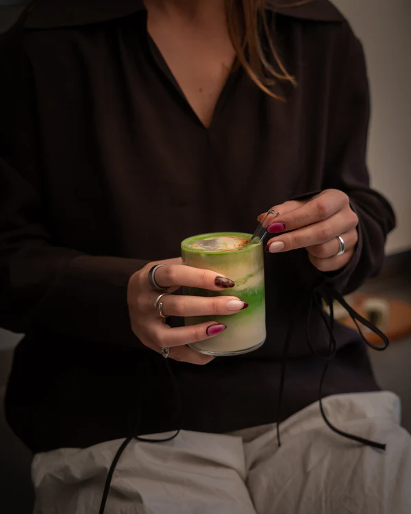 Close-up of a woman peacefully enjoying a bowl of vibrant green ceremonial matcha tea